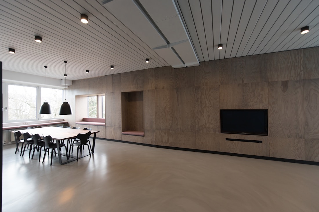 A warm wood-panelled meeting room with a table and pendant lights